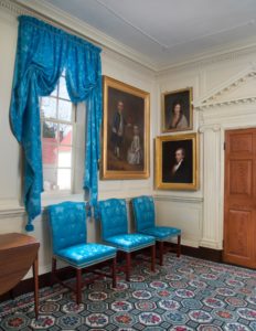 Fig. 10. Natalie Larson of Williamsburg, VA made the curtains using Saxon blue silk and worsted wool damask manufactured by Humphries Silk Weaving, of Sudbury, England. Portraits of Washington family members John Parke and Martha Parke Custis (by John Wollaston), Fanny Bassett Washington (by Robert Edge Pine), and Thomas Law (by Gilbert Stuart) hang on the walls.