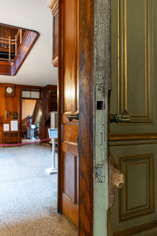 Figure 2. In the Breakfast Room, an ornately carved door with Louis XV-style hardware was backed on the other side, leading into the Butler’s Pantry, with oak paneling and a utilitarian lever.