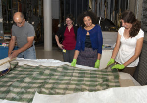Maureen Marton (center right) was the Decorative Arts Trust Curatorial Intern at the Munson-Williams-Proctor Arts Institute Museum of art (MWPAI). Here she evaluated the back of a crazy quilt with MWPAI staff. Photo by Richard Walker Photography.