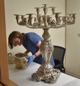 Christine Garnier examines a soup tureen and candelabra from the Mackay service at the W. M. Keck Museum at the University of Nevada, Reno.