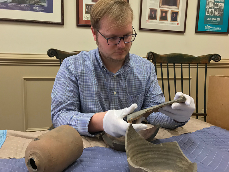 Figure 1. Drew Walton examining unidentified pottery shard, origin to be determined. All images are courtesy of William King Museum of Art unless otherwise noted.