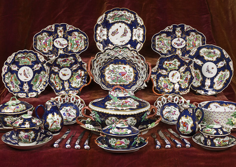A selection of pieces from the dinner and dessert china decorated in the LadyBetty Cobbe pattern, soft-paste Worcester porcelain, Cobbe Collection; the illustration shows a round dish, two oval dishes, a dessert plate, a meat plate, an oval dessert basket, two leaf dishes, a medium sized tureen and stand, two round dessert baskets, a large tureen and stand, a cream basin (shown without its pierced lid) and stand, two milk pots and lids, a sugar bowl and saucer, a small tureen and stand, a butter pot and stand, and four pairs of knives and forks.