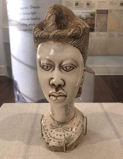 Grace M. Ford-Dirks is studying a bust of Nora August. Pictured: Bust of Nora August, 1865, St. Simons Island, GA. Ivory. Coastal Georgia Historical Society.