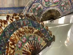 Figure 1. A display case at the Museo de Artes y Costumbres Populares in Seville features a 19th-century Spanish fan (rear) and an 18th-century imported Chinese fan (front). Photo by author.