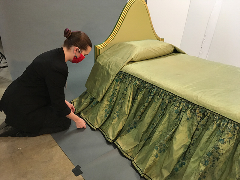Figure 8. Textile Conservator Chandra Obie Linn fixing the skirt of a bedspread from the Wormser bedroom during a photoshoot.