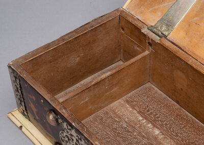 Corresponding pinholes above the smaller interior compartment suggest the compartment originally had a lid.
