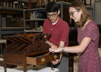 Historic Deerfield curator Daniel Sousa and Mary Orms study an English canterbury. (1810-1815. Mahogany, white oak, sylvestris pine, bald cypress, white pine; base metal: brass. Historic Deerfield, Gift of Mark S. Cluett, HD 2001.29.8.)