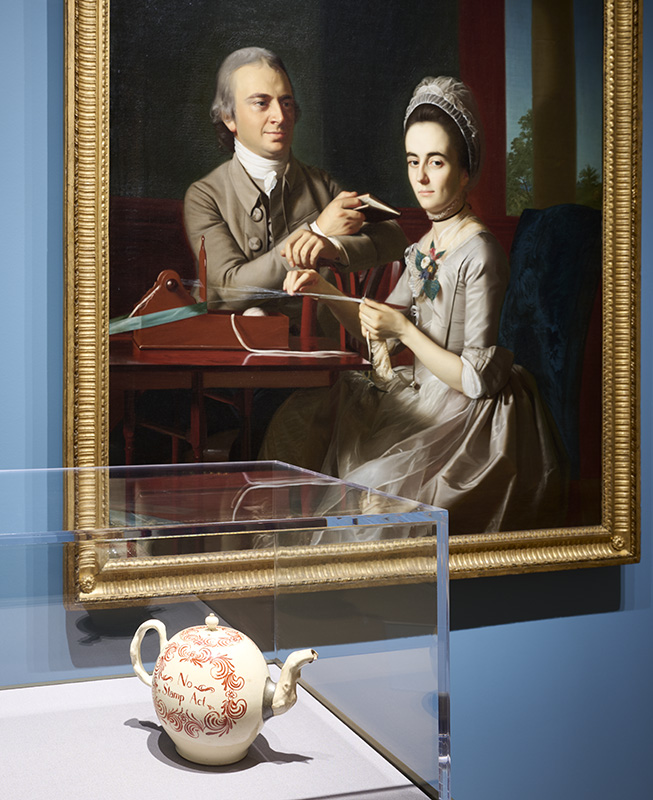 Figure 3. Stamp Act Teapot. England, probably Staffordshire, 1766–70. Lead-glazed earthenware (creamware) with enamel decoration and lettering. Middleton Family Collection on loan to the Philadelphia Museum of Art. John Singleton Copley, 𝘗𝘰𝘳𝘵𝘳𝘢𝘪𝘵 𝘰𝘧 𝘛𝘩𝘰𝘮𝘢𝘴 𝘢𝘯𝘥 𝘚𝘢𝘳𝘢𝘩 𝘔𝘰𝘳𝘳𝘪𝘴 𝘔𝘪𝘧𝘧𝘭𝘪𝘯 (detail), 1773, Boston, MA. Oil on ticking. Philadelphia Museum of Art, EW1999-45-1. Photo by Sarah Croop.