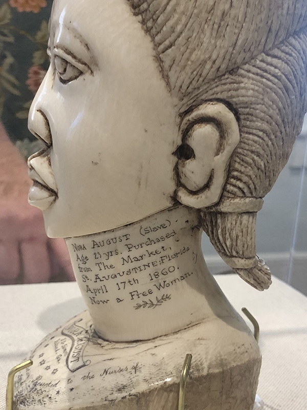 Detail of the 𝘉𝘶𝘴𝘵 𝘰𝘧 𝘕𝘰𝘳𝘢 𝘈𝘶𝘨𝘶𝘴𝘵 showing the text: “Nora August (Slave). Age 23 yrs. Purchased from The Market, St. Augustine, Florida April 17th 1860. Now a Free Woman.” Photo by author.